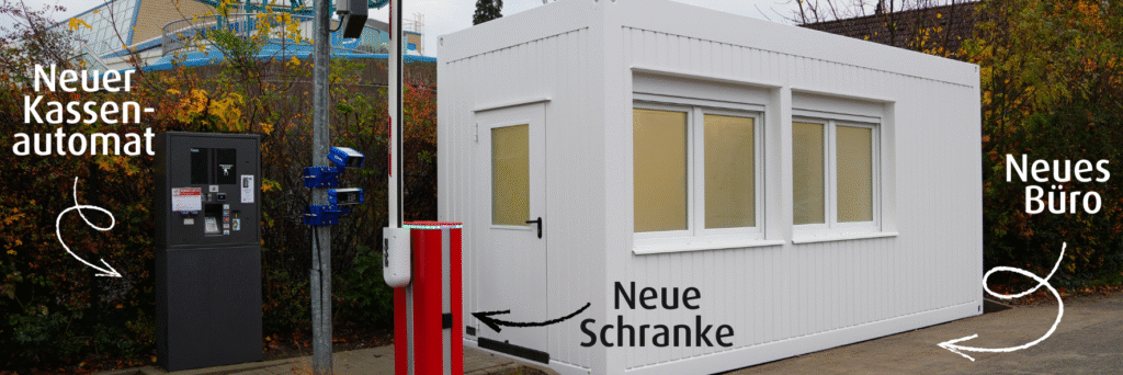 Ein zum Büro umgebauter Container. Daher steht ein Kassenautomat und eine geöffnete Schranke.