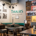Restauranttische mit Sitzecke und einer Wand voller Bilder und Alkoholflaschen