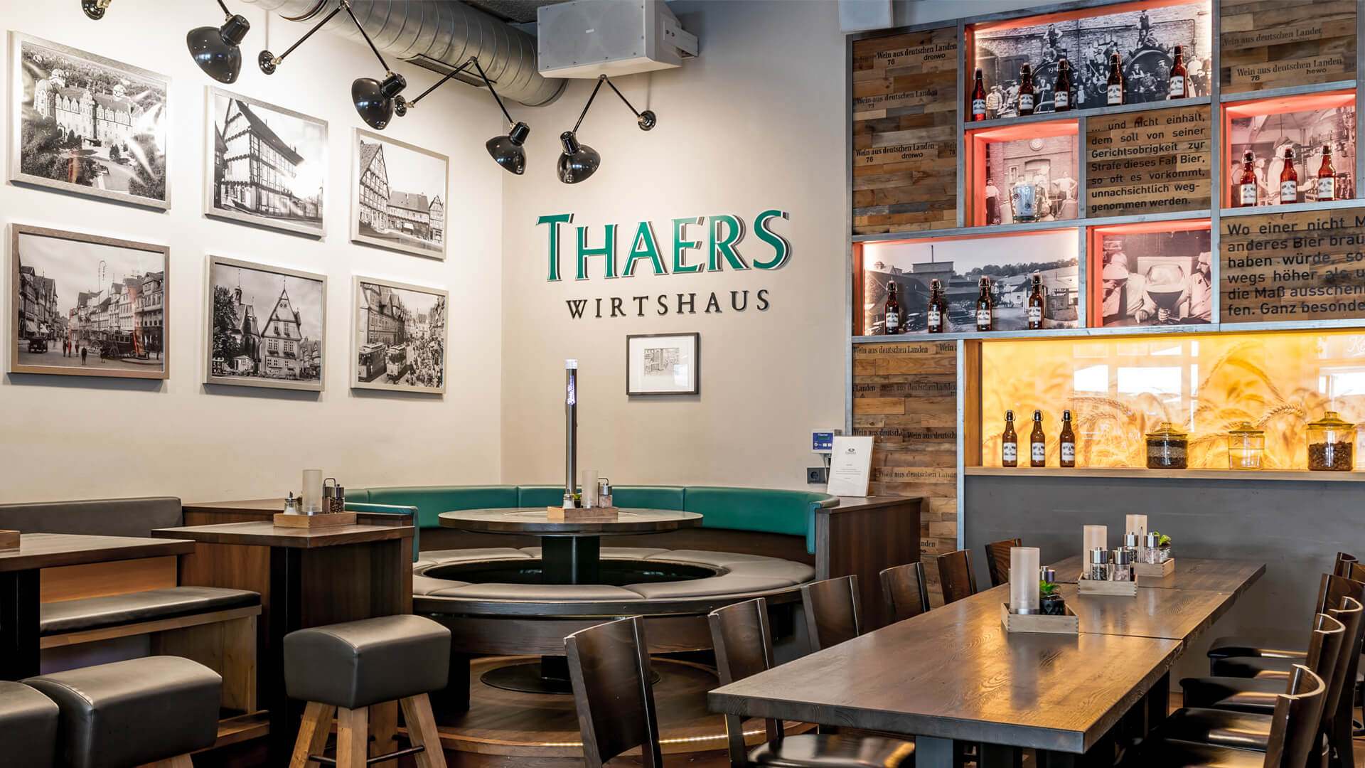 Restauranttische mit Sitzecke und einer Wand voller Bilder und Alkoholflaschen