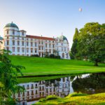 Blick auf das Schloss Celle mit saftig grüner Wiese und einem Wassergraben im Vordergrund.