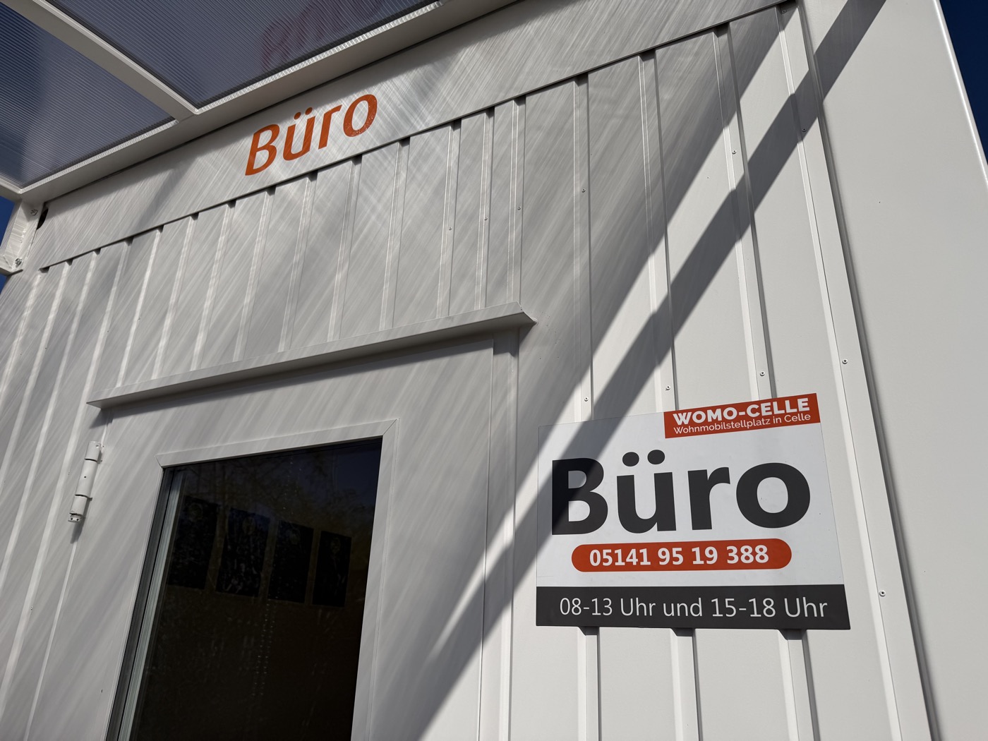 Büro-Container mit Bild der Öffnungszeiten und Telefonnummer